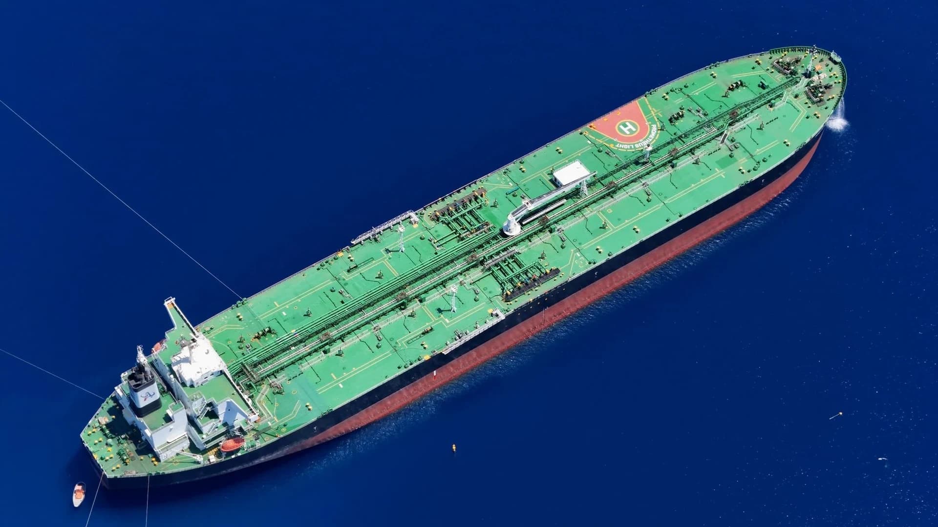 A large oil tanker ship illuminated at night, docked at a harbor.